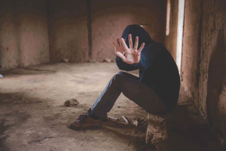 Drug addict with hand in front of his face