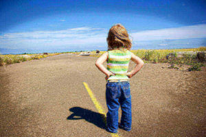 Child standing alone on a road