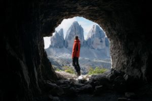 man in cave looking at mountains