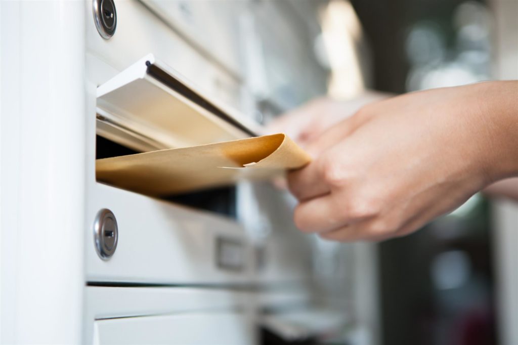 woman inserting envelope in mailbox