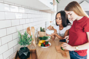 Women in kitchen preparing salad