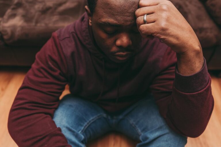 a person struggling with the effects of meth sits down and holds their head