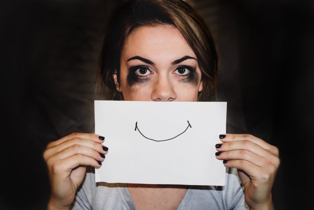 woman with smeared eye makeup holds a paper with a smile