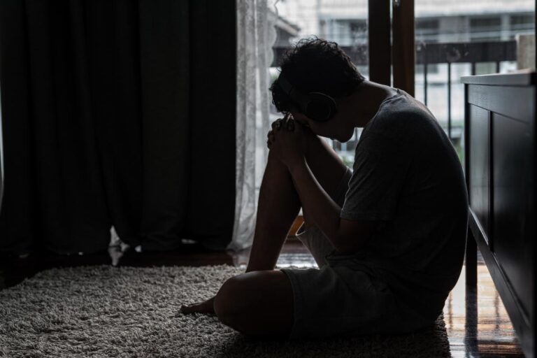 a person sits on the floor dealing with addiction triggers