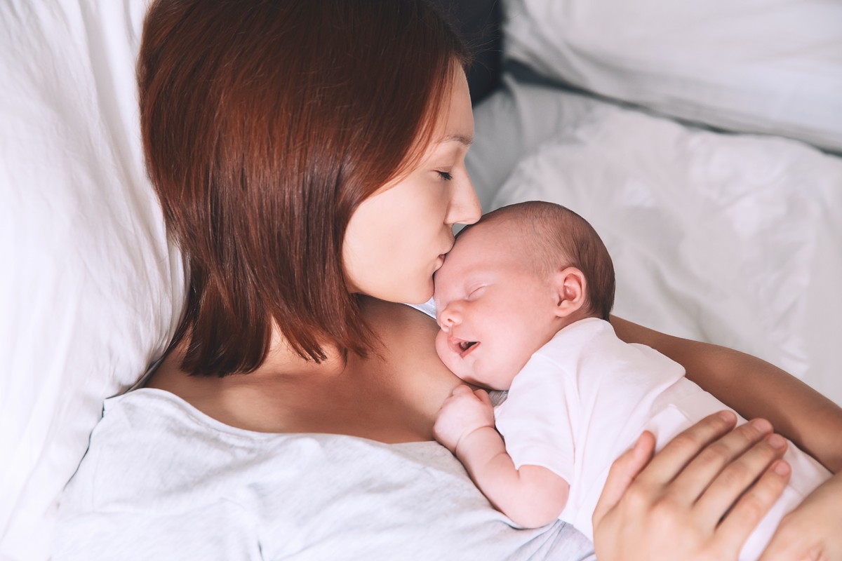 mother kissing her newborn baby