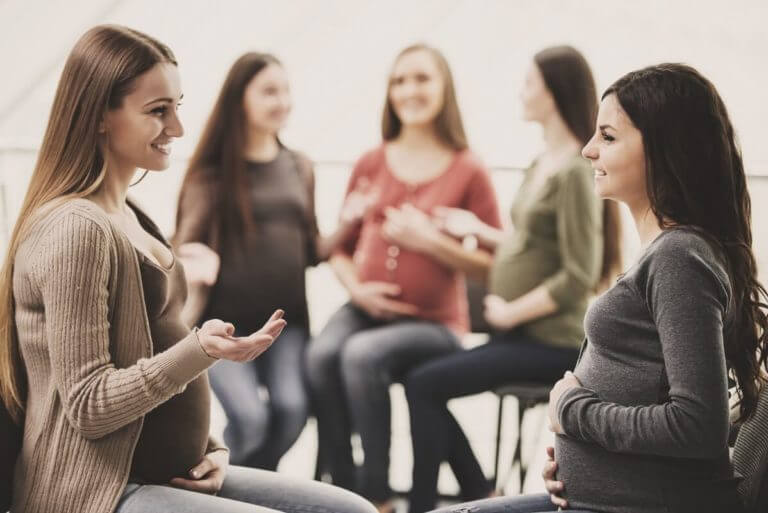 happy pregnant women are talking together at antenatal class