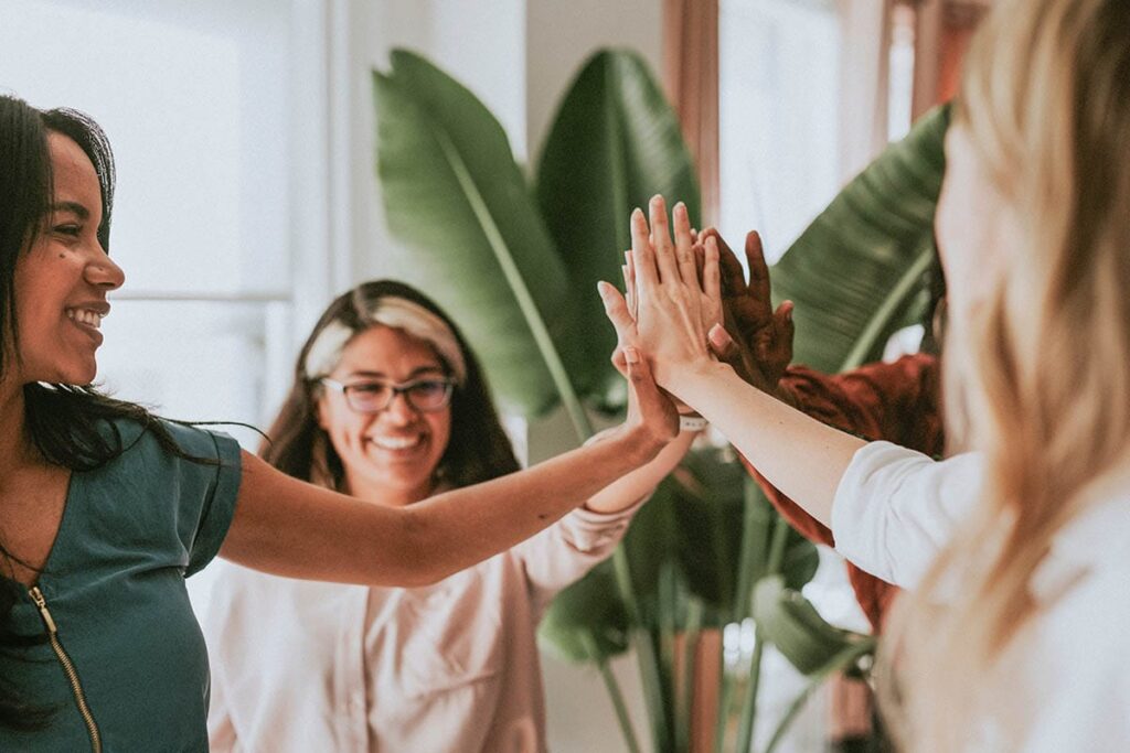 a group of women high five during national women's health month