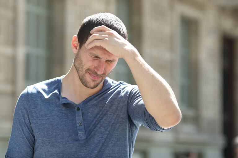 Person with hand on forehead, wondering, "What are the physical signs of alcoholism?"